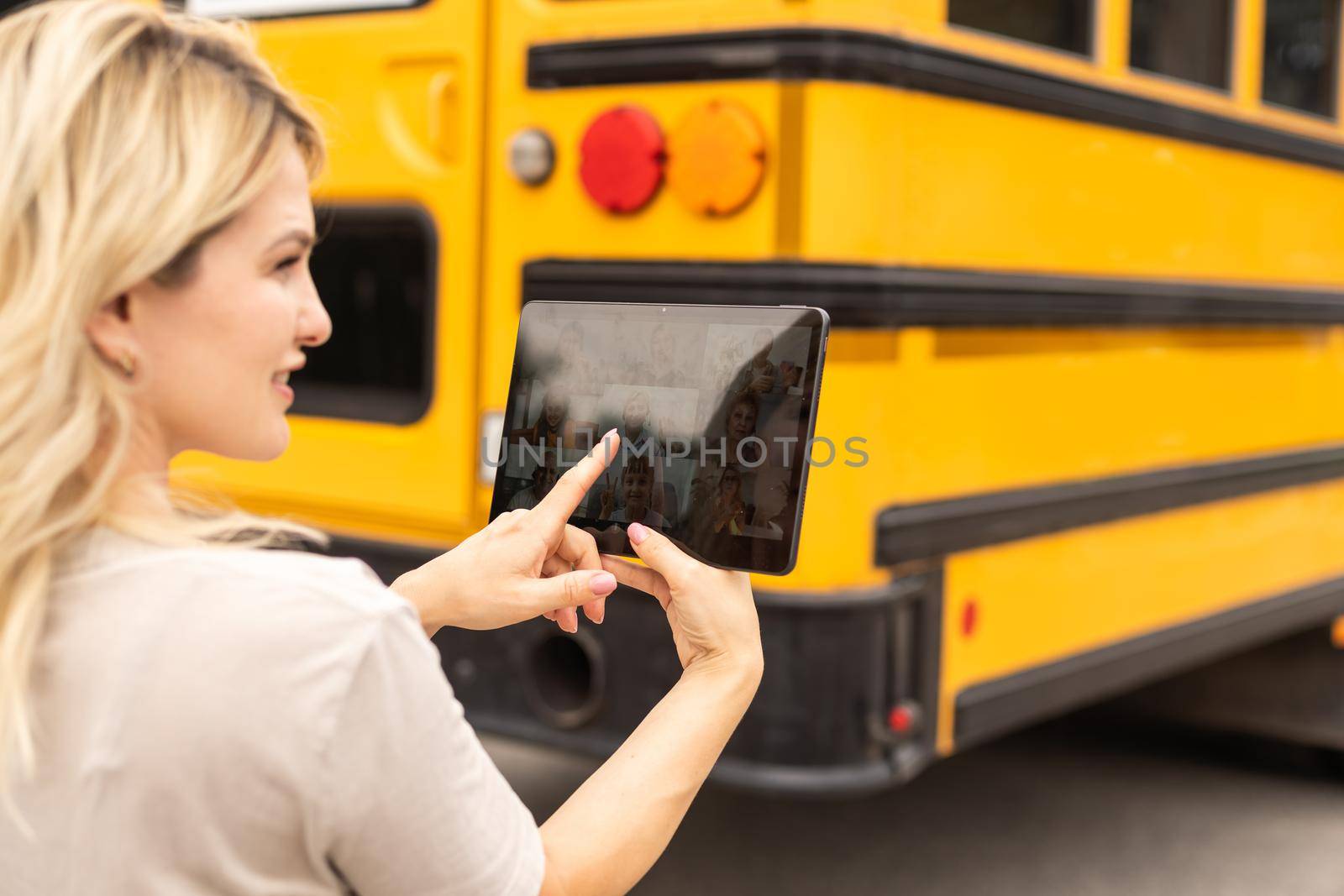 Female Teacher Or Student With Digital Tablet near the school bus. video chat.