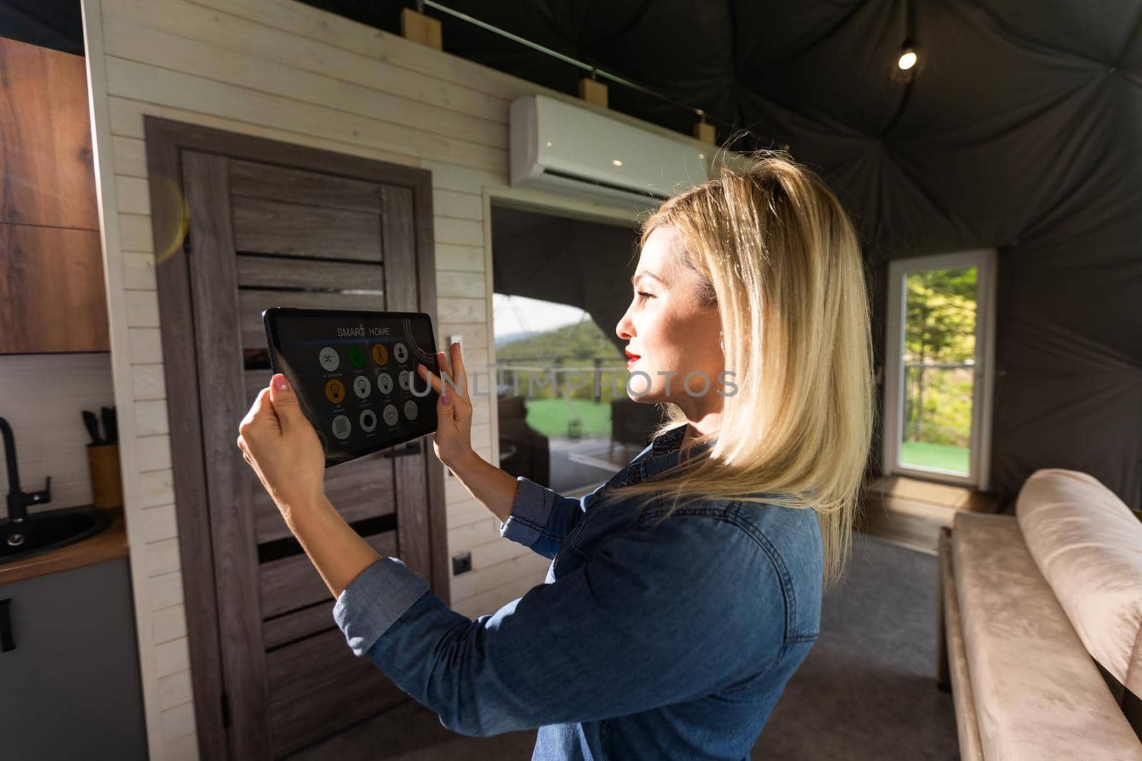 woman holding a tablet with the smart home application in a glamping dome tent domestic.
