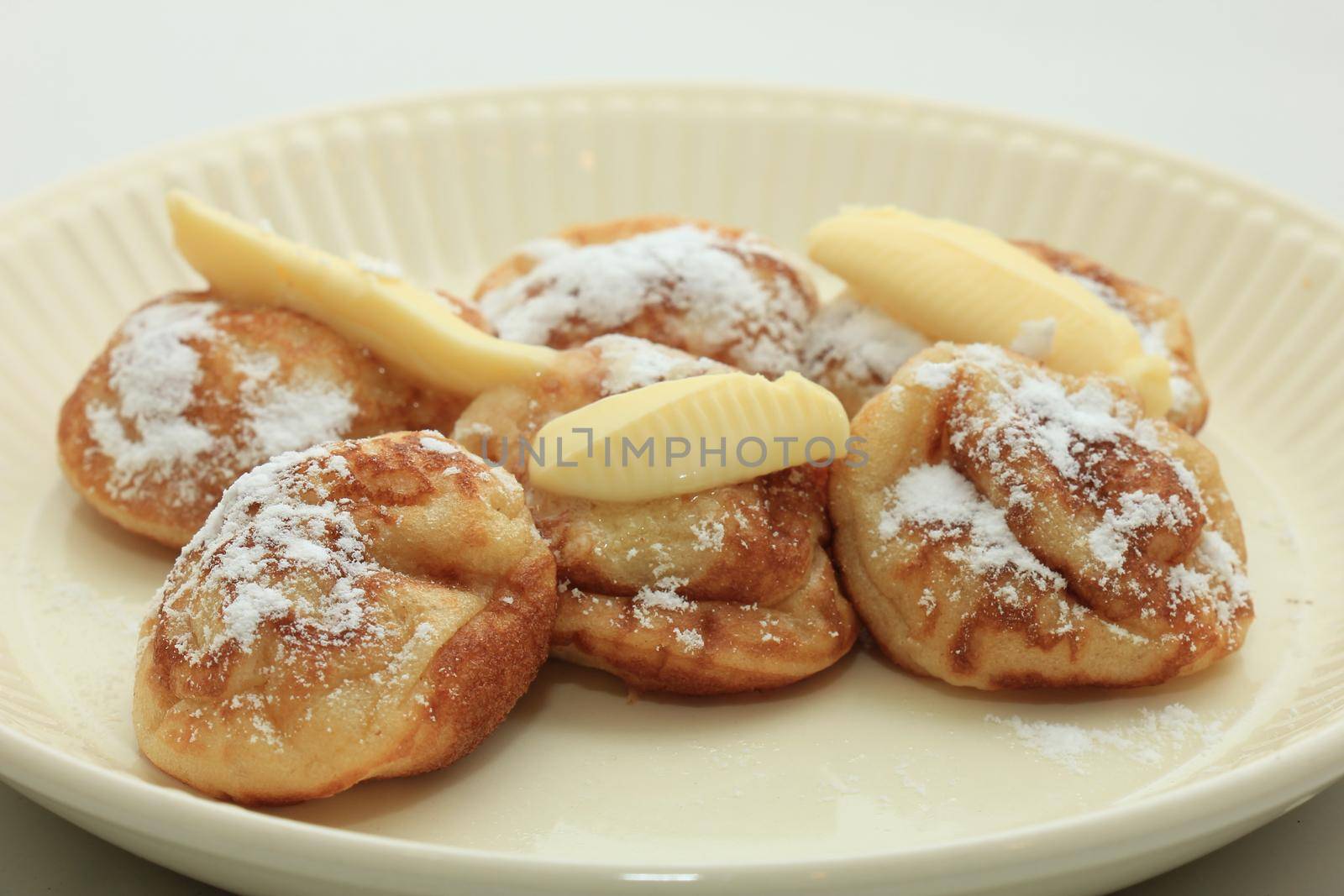 Poffertjes, Dutch small, fluffy pancakes, served with powdered sugar and butter.