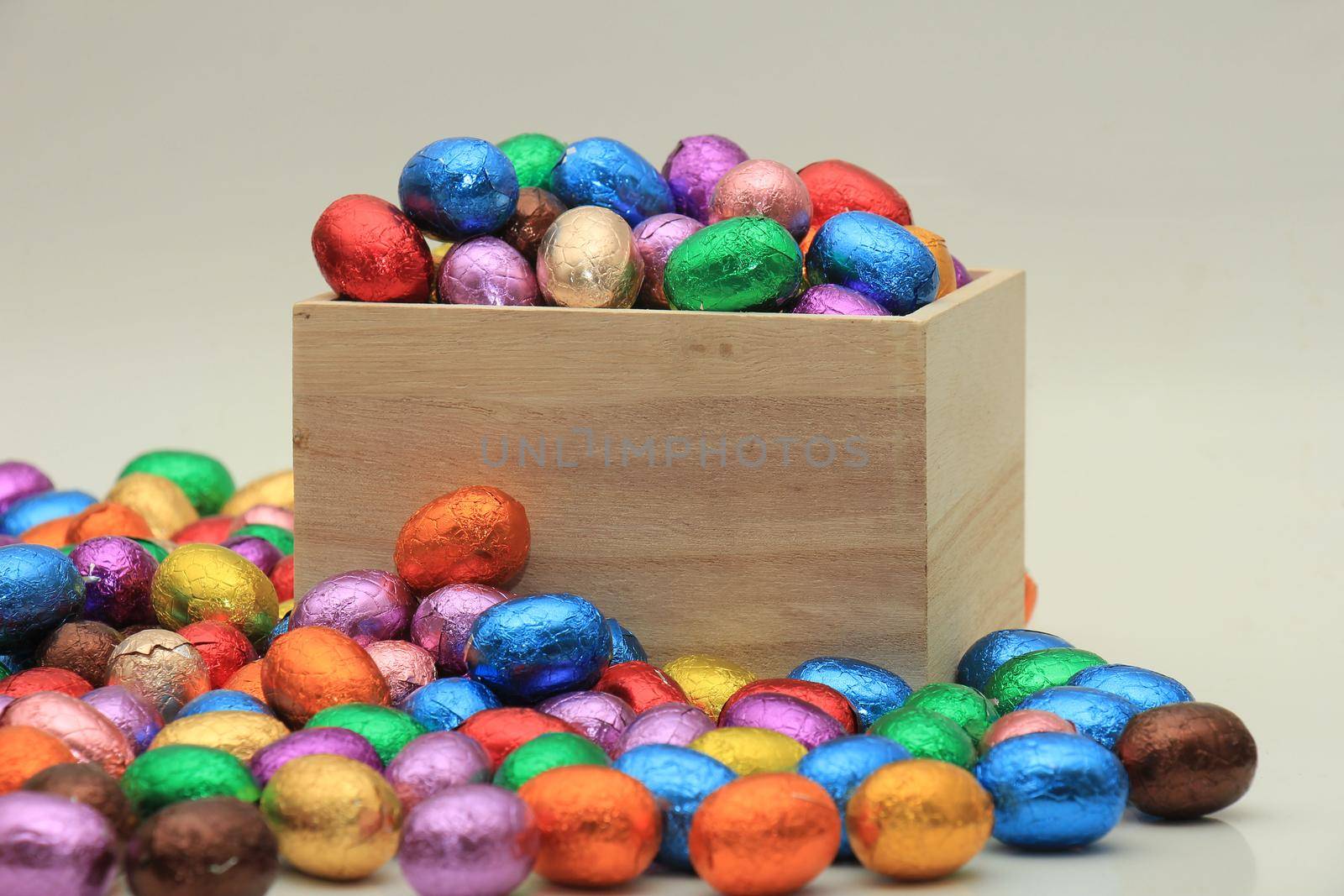 Foil wrapped chocolate easter eggs in a wooden box by studioportosabbia