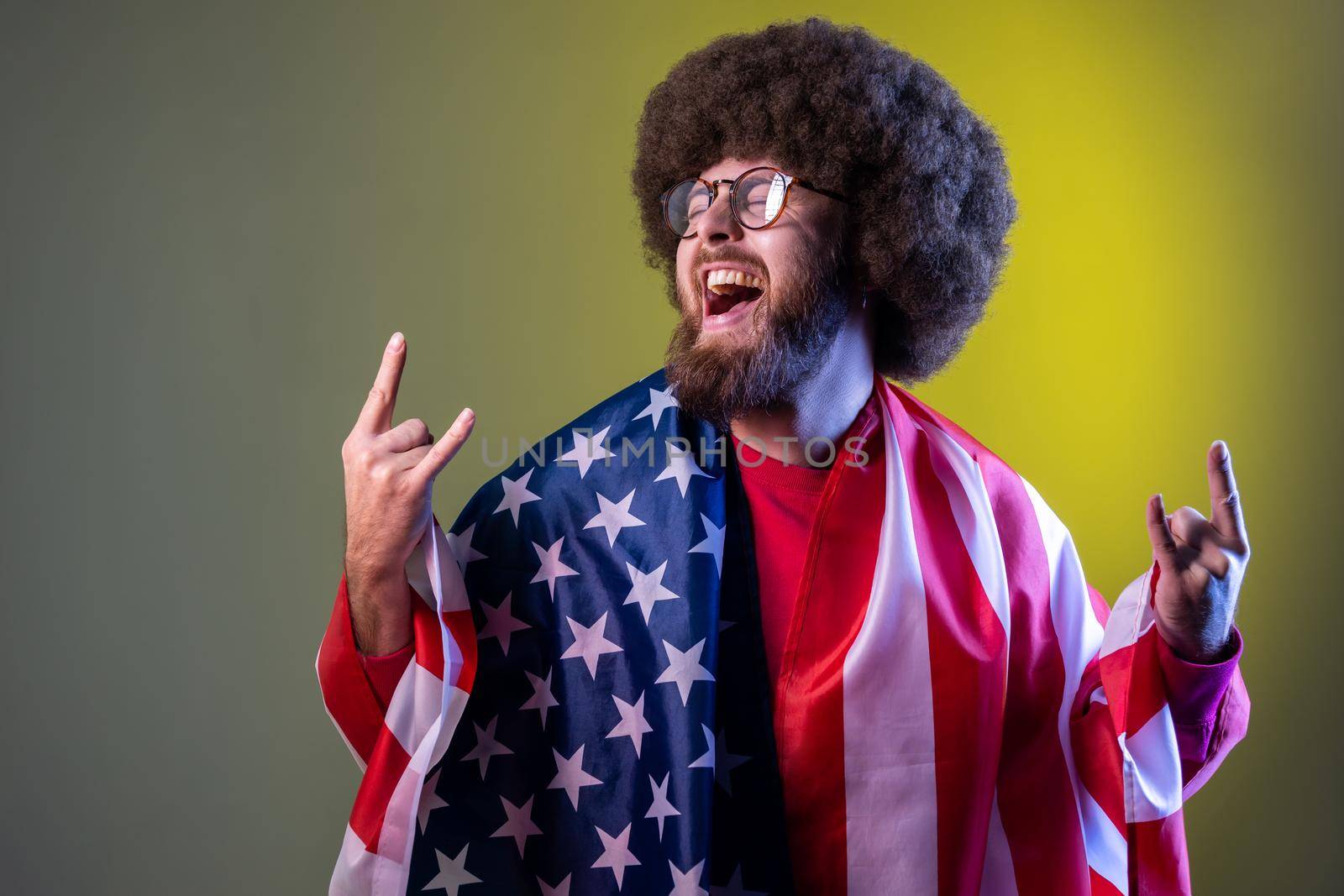 Hipster man with Afro hairstyle wrapped in american flag, rejoicing, celebrating national holiday, by Khosro1