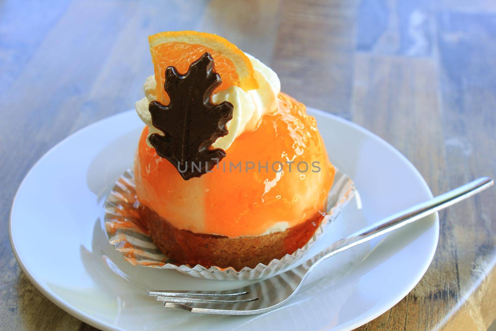 Fresh orange mousse confectionery, with cream and a chocolate decoration