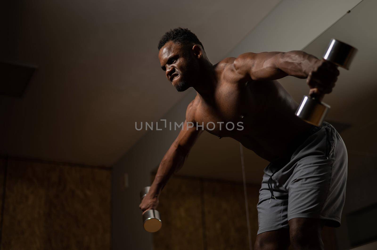 Attractive african american man doing arm exercises with dumbbells