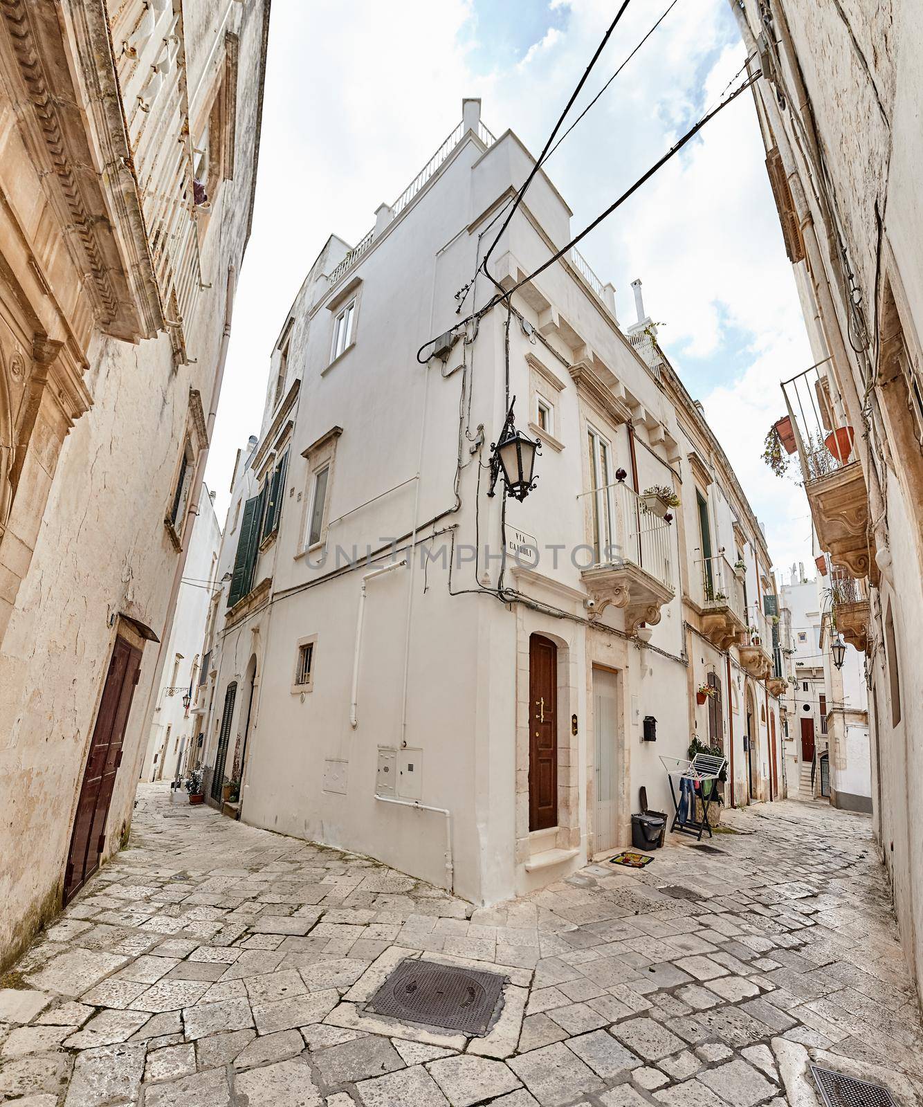 Wonderful architecture of an ancient streets decorated with plants in flowerpots. Downtown, white city Ostuni, Bari, Italy. Tourism, travel concept.