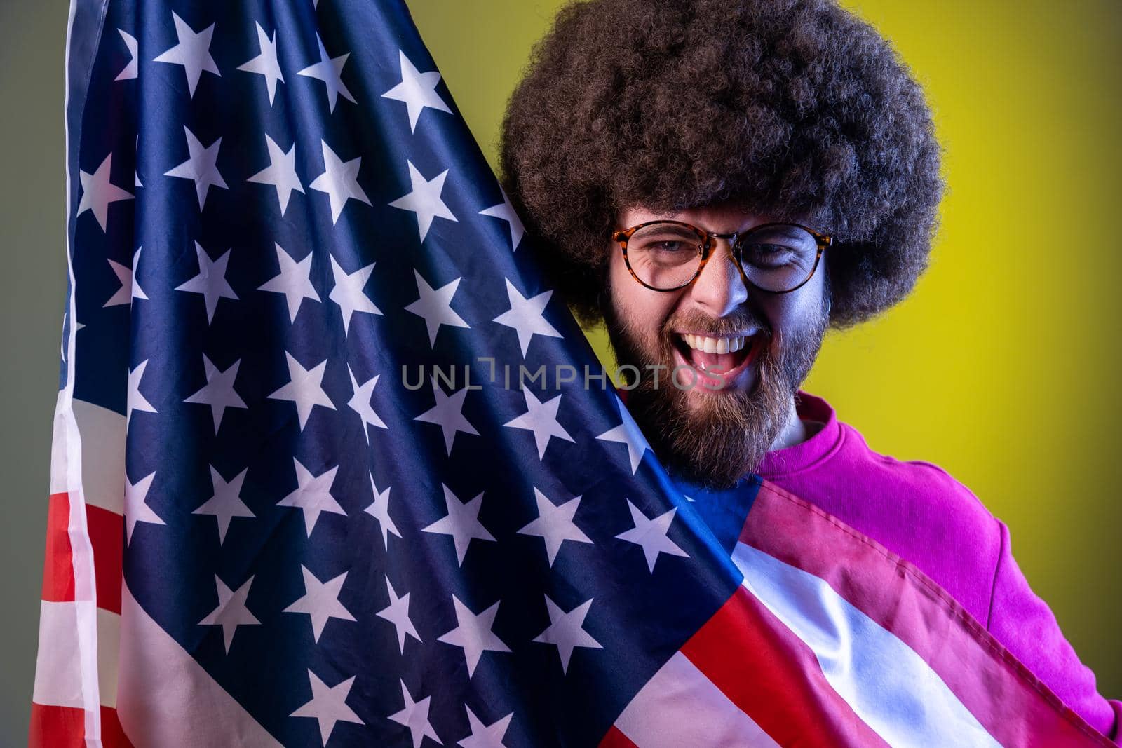 Man with Afro hairstyle having fun, holding american flag, rejoicing, celebrating national holiday. by Khosro1