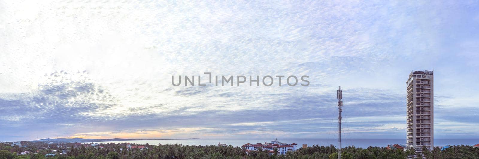 Long panorama banner. Light soft blue orange sunrise reflections dramatic sky cumulus clouds. Early rising in the city. High skyscraper multi-storey building, antenna. Morning calm time.