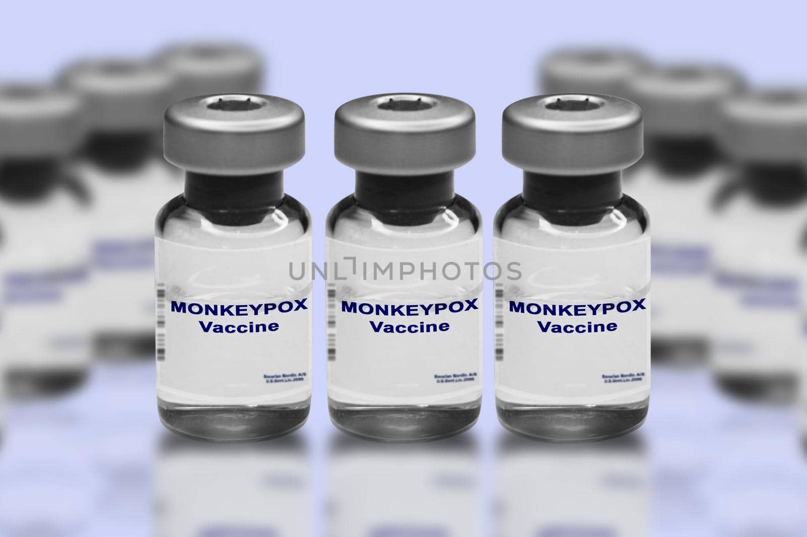 Monkeypox vaccine close-up on a light mirror background. In the background are blurred vaccine vials..
