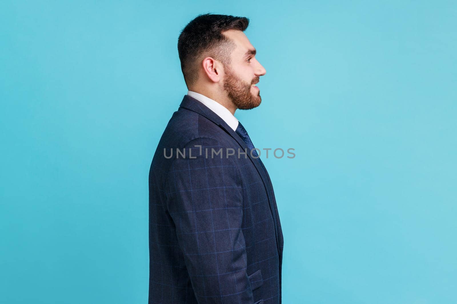 Profile portrait of young adult handsome bearded businessman wearing official style suit looking ahead with toothy smile, optimism, success. by Khosro1