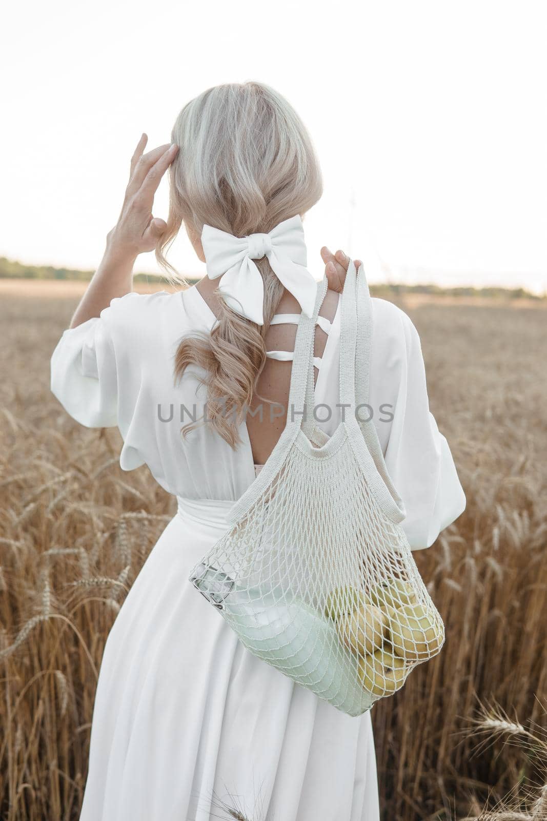 A blonde woman in a long white dress walks in a wheat field. The concept of a wedding and walking in nature by Annu1tochka