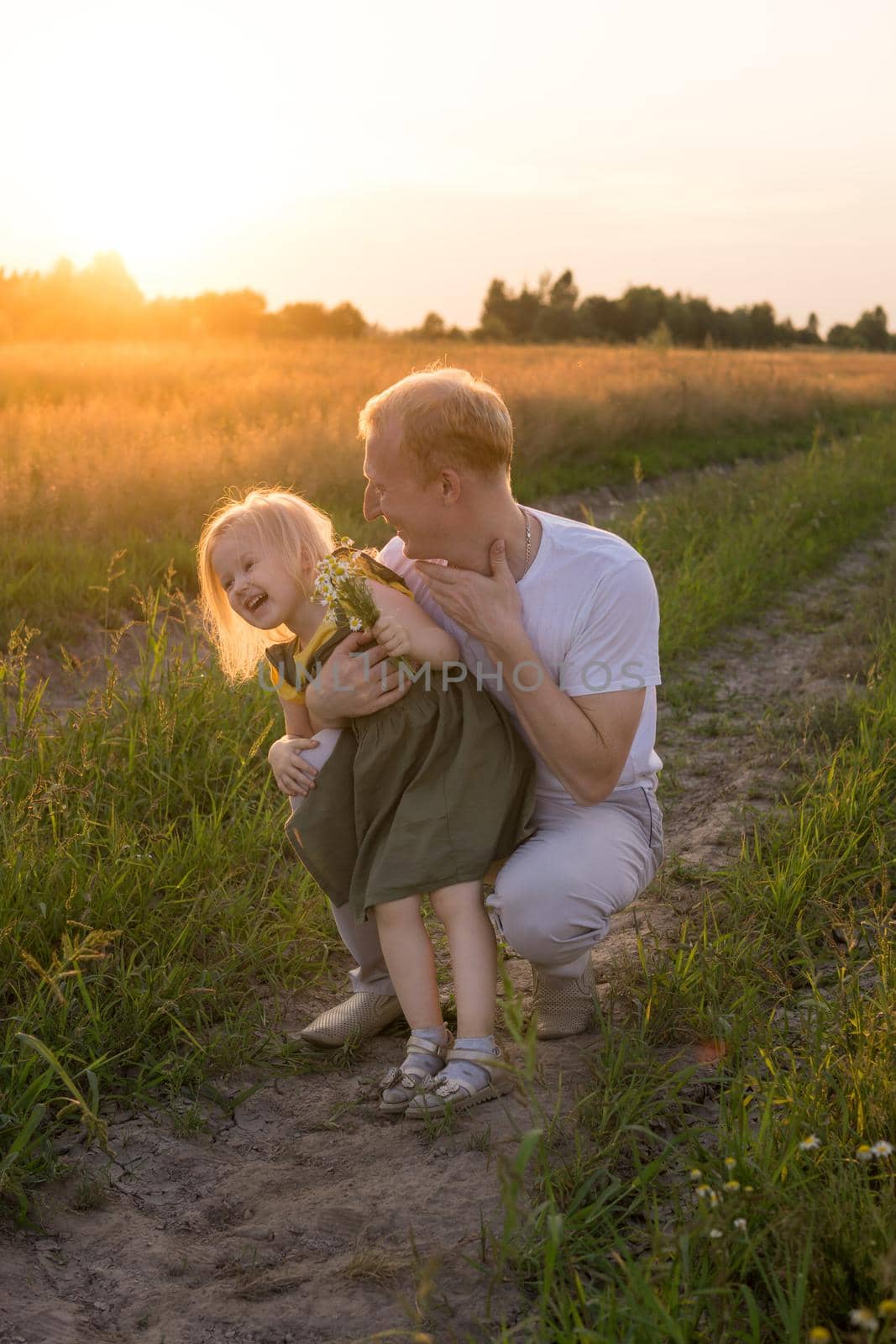 Dad and his blonde daughter are walking and having fun in a chamomile field. by Annu1tochka