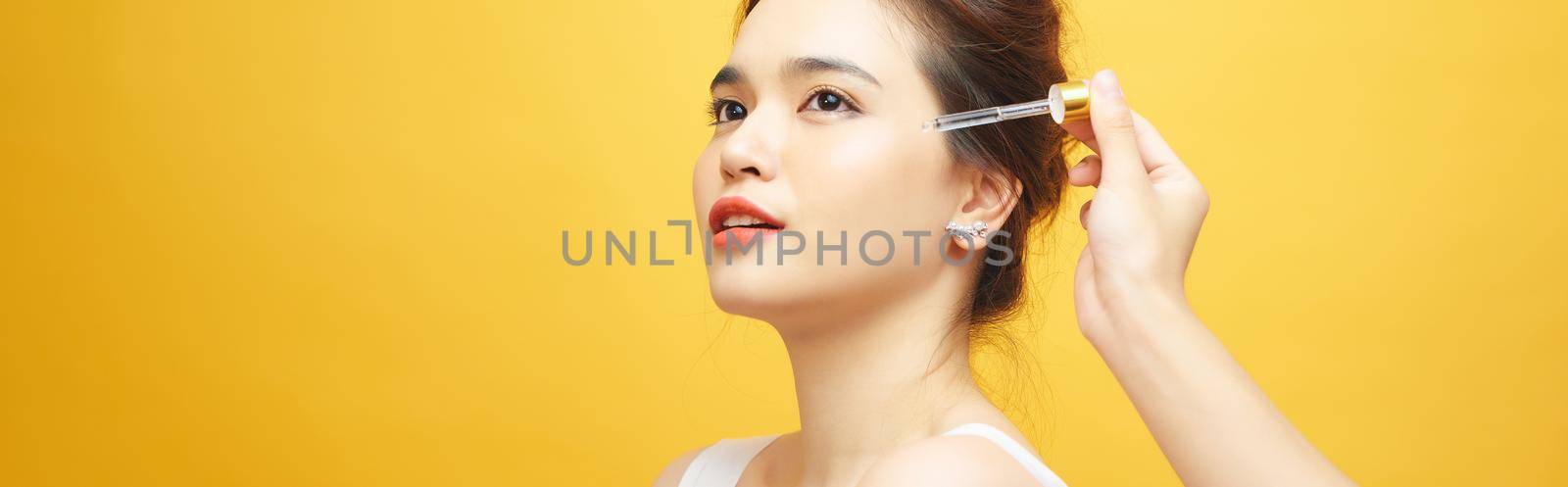 Pretty Caucasian woman putting cosmetic serum on her face at bathroom