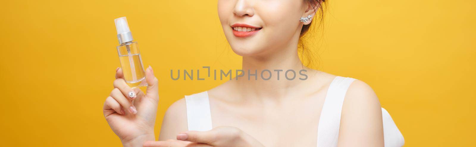 Beautiful asian woman standing , holding spray bottle, Yellow background by makidotvn