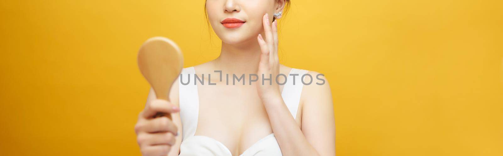 Asian woman holding and looking in classical wooden mirror.