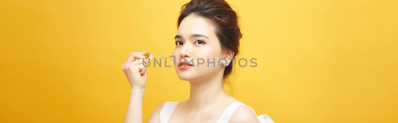Beautiful model applying a cosmetic skin serum on her skin