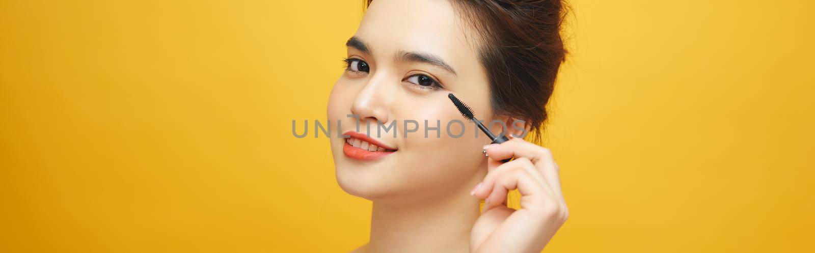 Women who make up makeup, eyelashes, mascara on yellow background by makidotvn