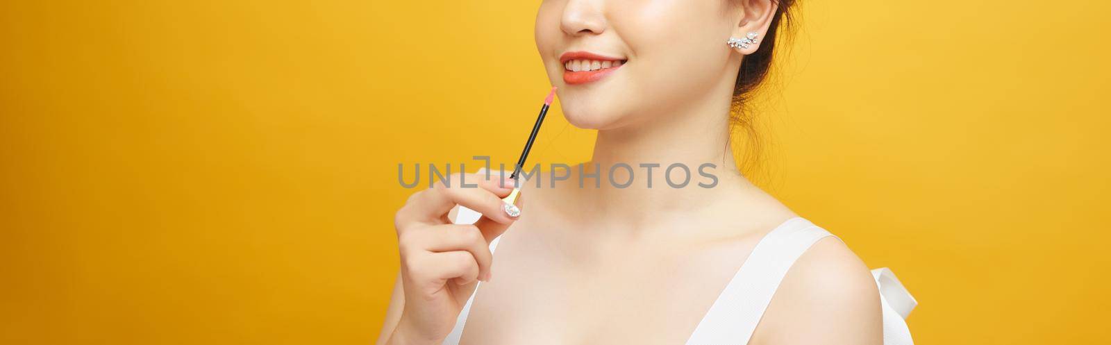 Beautiful woman applying red lipstick