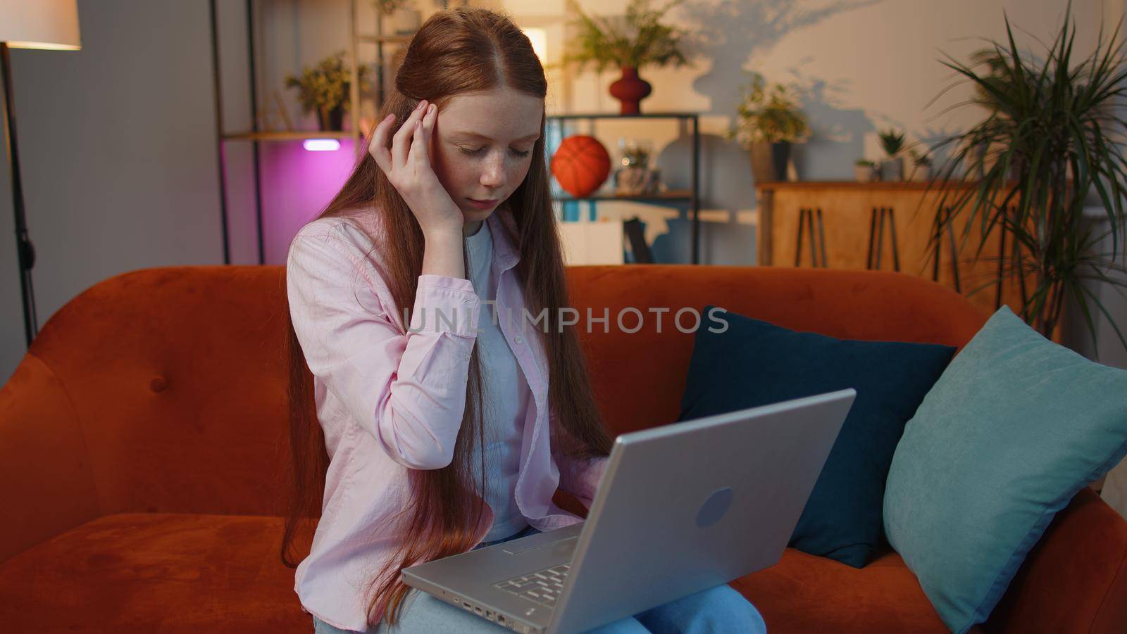 Tired young teen child girl freelancer use laptop, suffering from headache problem tension and migraine, stress. Ginger kid works on notebook, sends messages, makes online purchases, watching movies