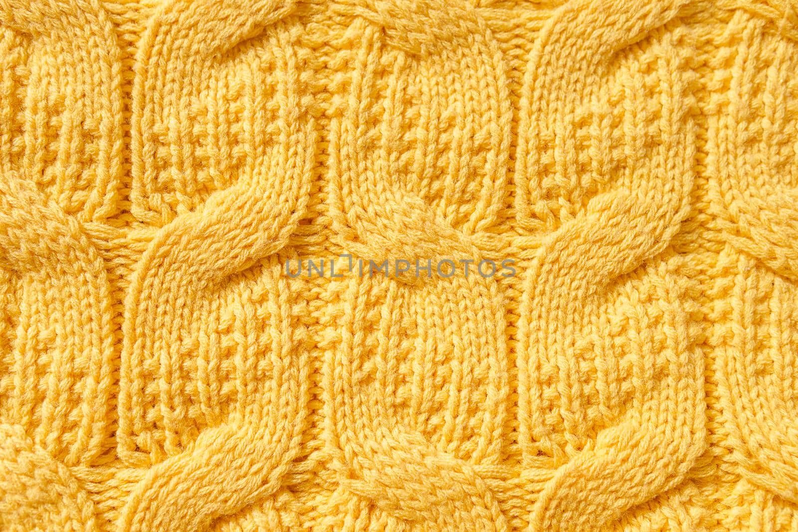 The texture of a warm knitted sweater. The perfect background is yellow. Close-up.