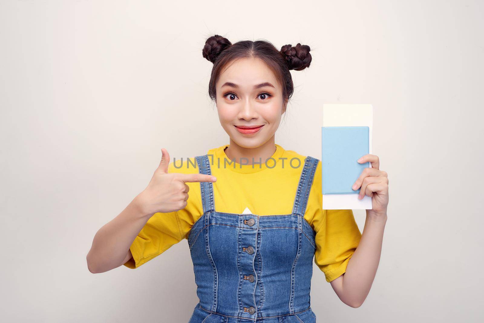 Attractive excited woman 20s smiling while holding passport with travel tickets isolated over white background