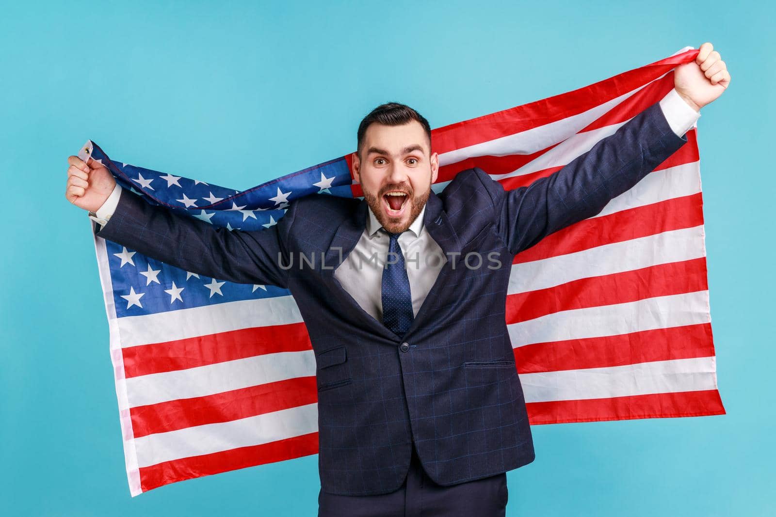 Extremely happy man with beard wearing official style suit holding USA flag and screaming happily, looking at camera, celebrating national holiday. by Khosro1