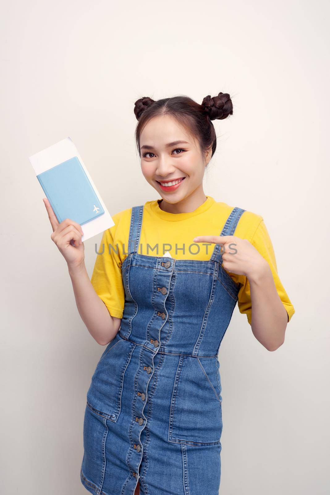 Attractive excited woman 20s smiling while holding passport with travel tickets isolated over white background