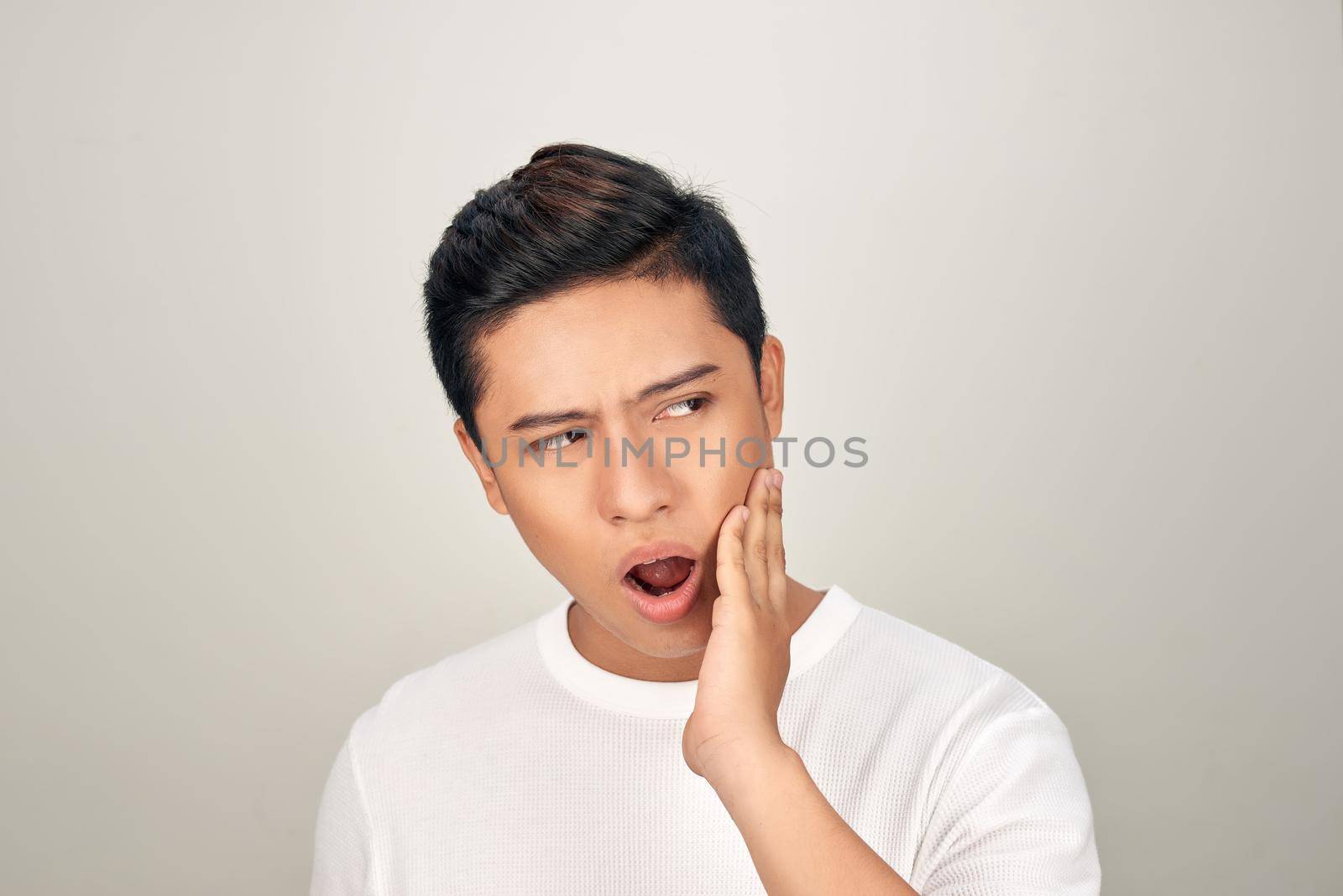Portrait of Asian men with worry eyes use hand touching his cheek , feelings pain from toothache. Tooth and mouth disease concept.