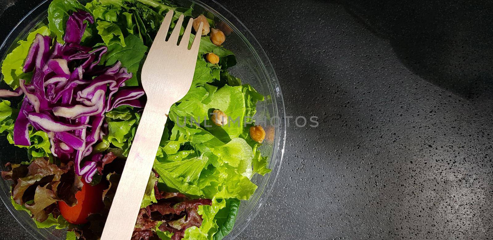 Healthy vegetable salad of fresh tomato, lettuce and red cabbage with wooden spoon and caesar salad dressing Diet menu Top view