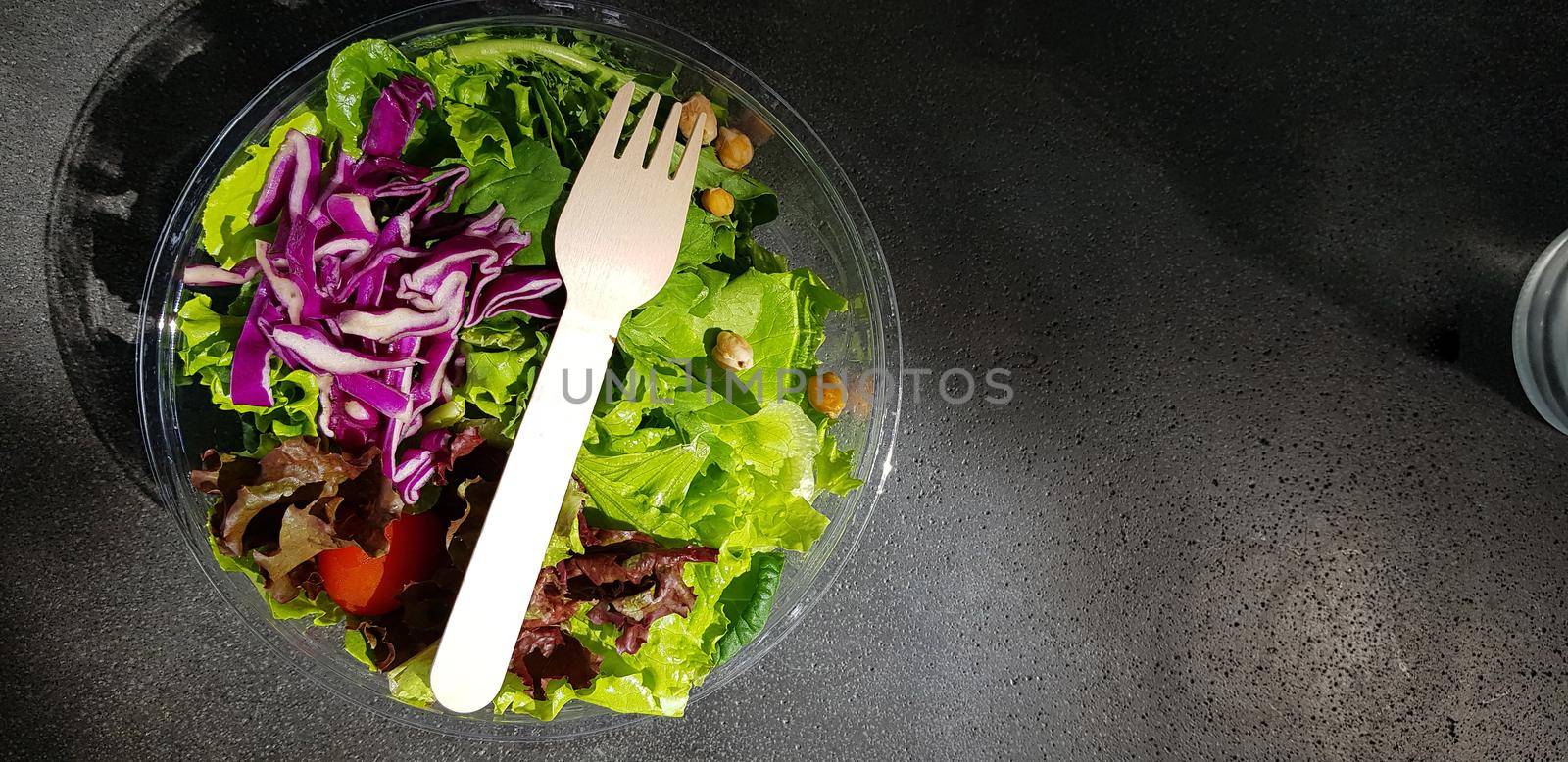 Healthy vegetable salad of fresh tomato, lettuce and red cabbage with wooden spoon and caesar salad dressing Diet menu Top view