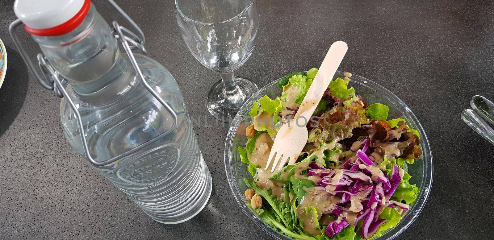 Healthy vegetable salad of fresh tomato, lettuce and red cabbage with wooden spoon and caesar salad dressing Diet menu Top view