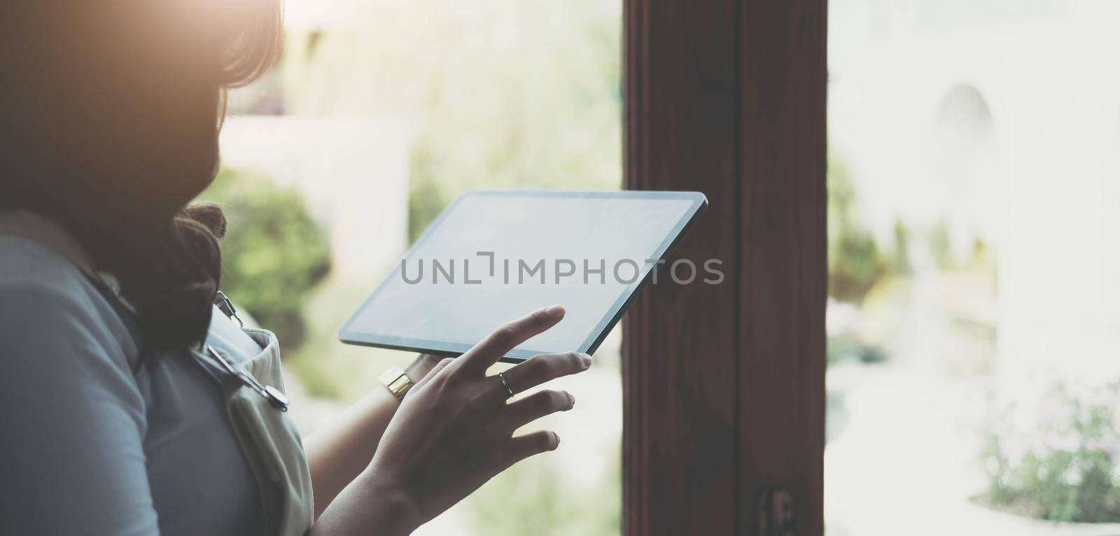 Mockup image of a woman holding digital tablet with blank white desktop screen.