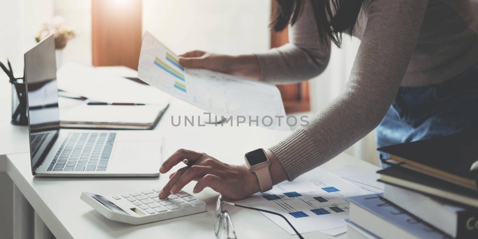 Close up woman using calculator and laptop for do math finance on wooden desk in office and business working background, tax, accounting, statistics and analytic research concept.