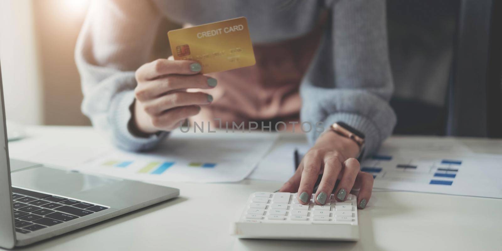 Close up man using calculator and holding credit card at home. by wichayada