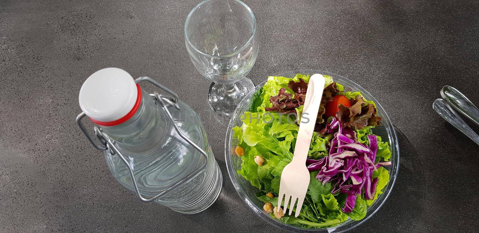 Healthy vegetable salad of fresh tomato, lettuce and red cabbage with wooden spoon and caesar salad dressing Diet menu Top view