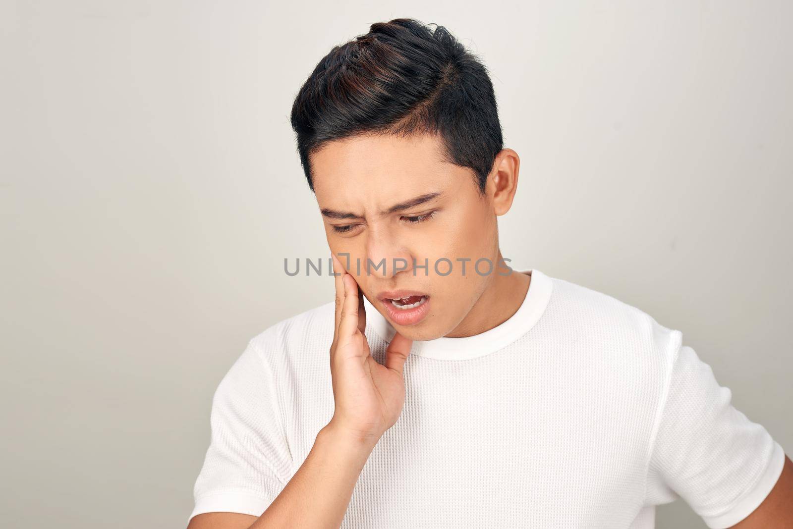 Portrait of Asian men with worry eyes use hand touching his cheek , feelings pain from toothache. Tooth and mouth disease concept.