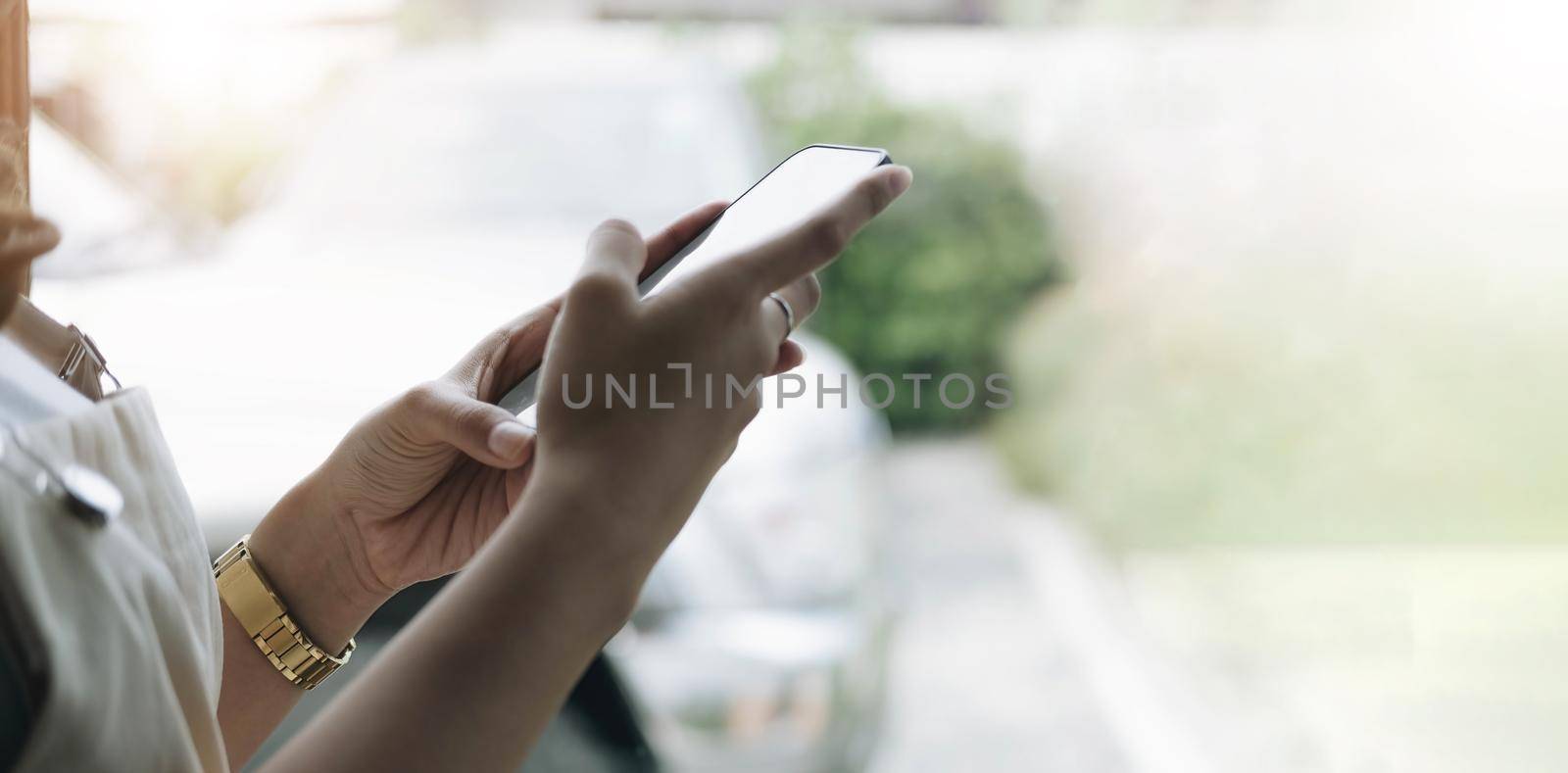 Back view close up of a woman hand using a smart phone with blank screen lying on a couch at home.
