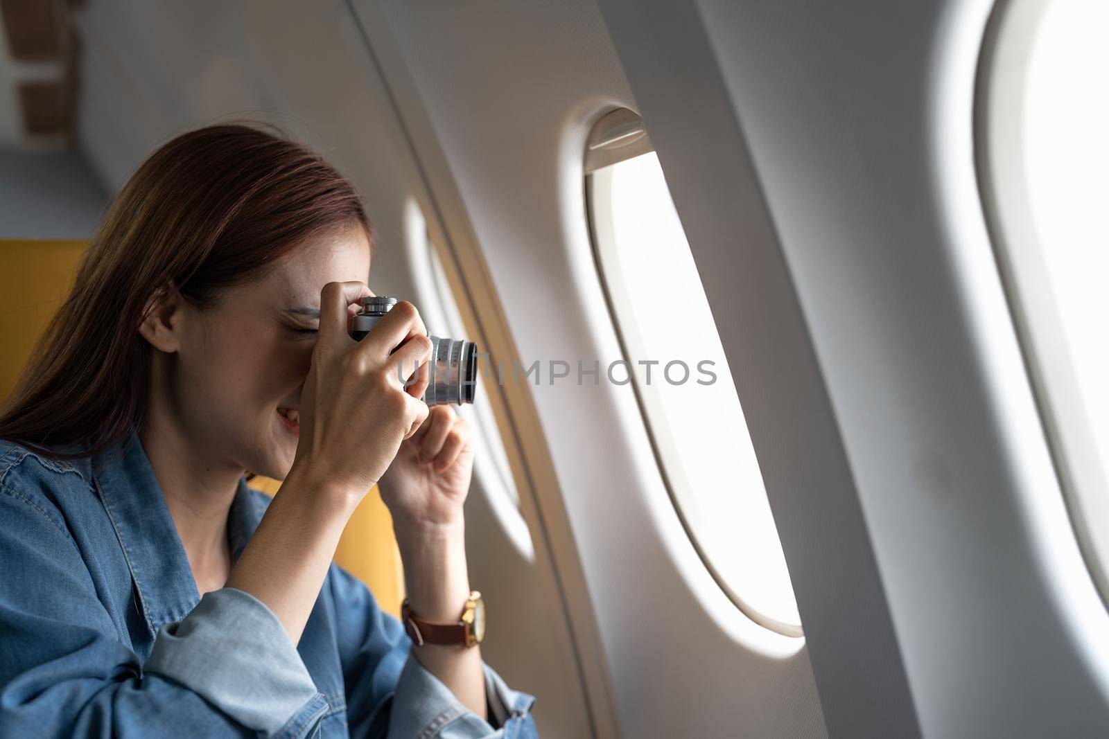 Beautiful Asian woman take a photo with camera in airplane by nateemee