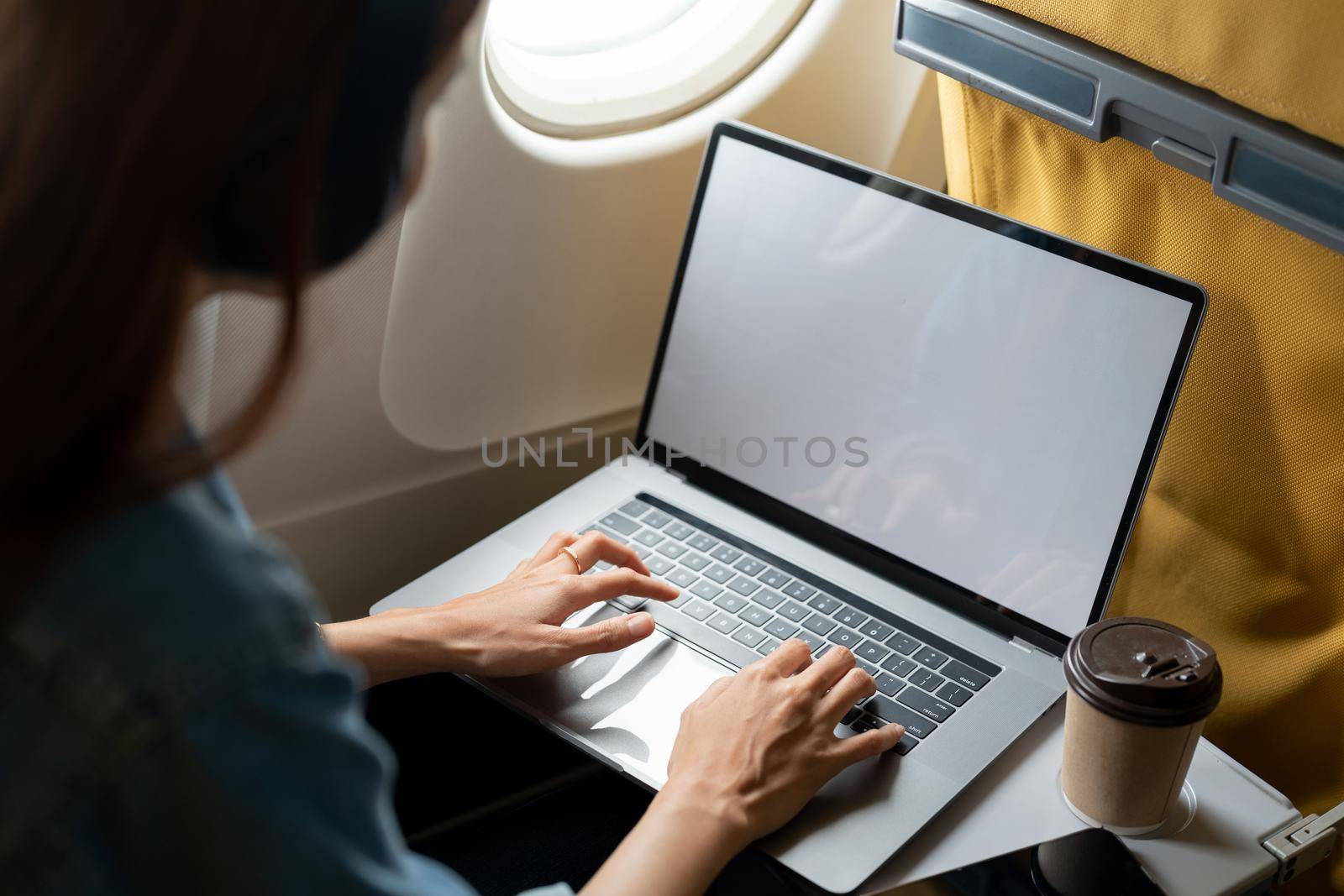 Beautiful asian travel woman using laptop computer in airplane by nateemee