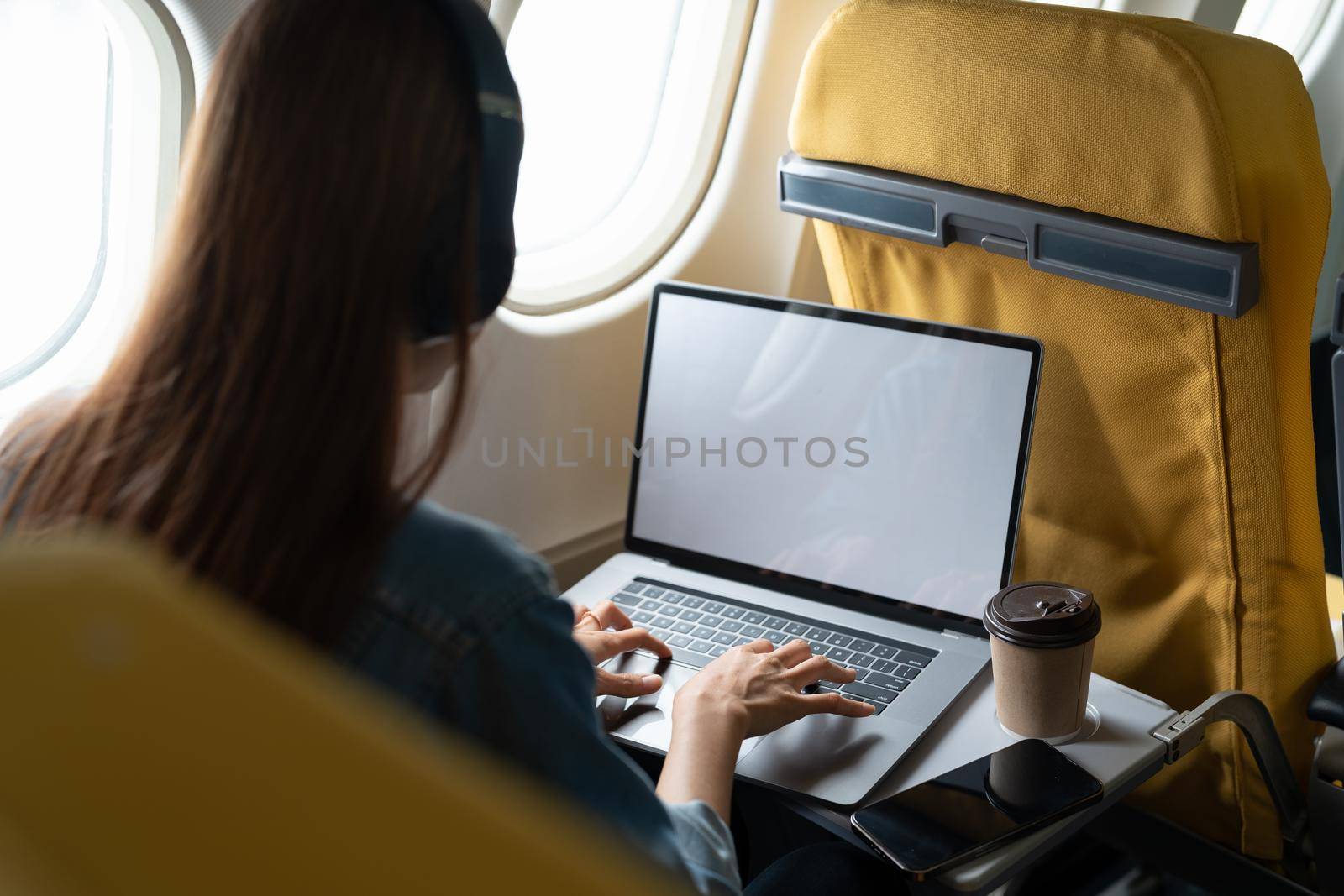 Beautiful asian travel woman using laptop computer in airplane by nateemee