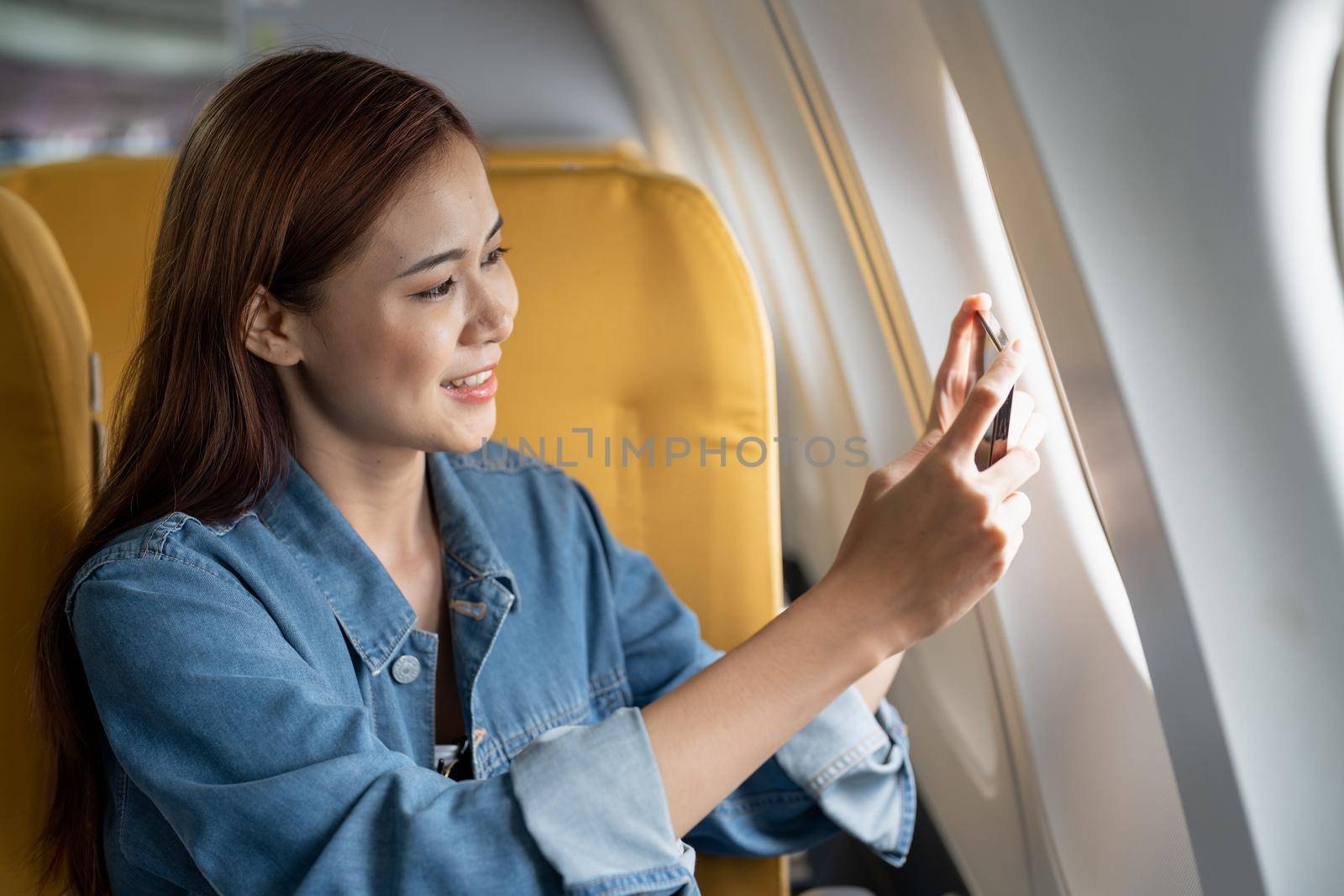 Beautiful Asian woman take a photo with mobile phone in airplane.