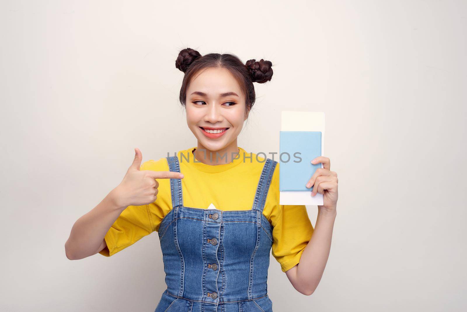 Attractive excited woman 20s smiling while holding passport with travel tickets isolated over white background