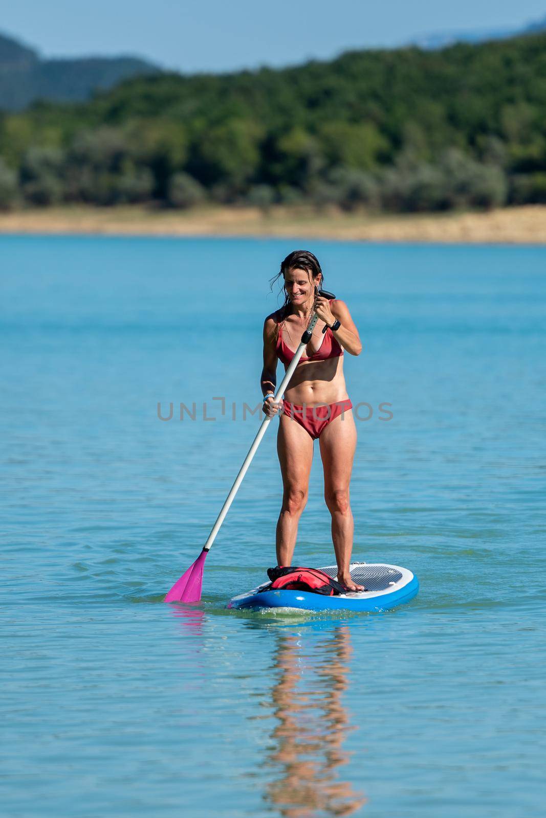 Woman Paddle Surfing on Lake Montbel in Ariege with the boats in the summer of 2022.