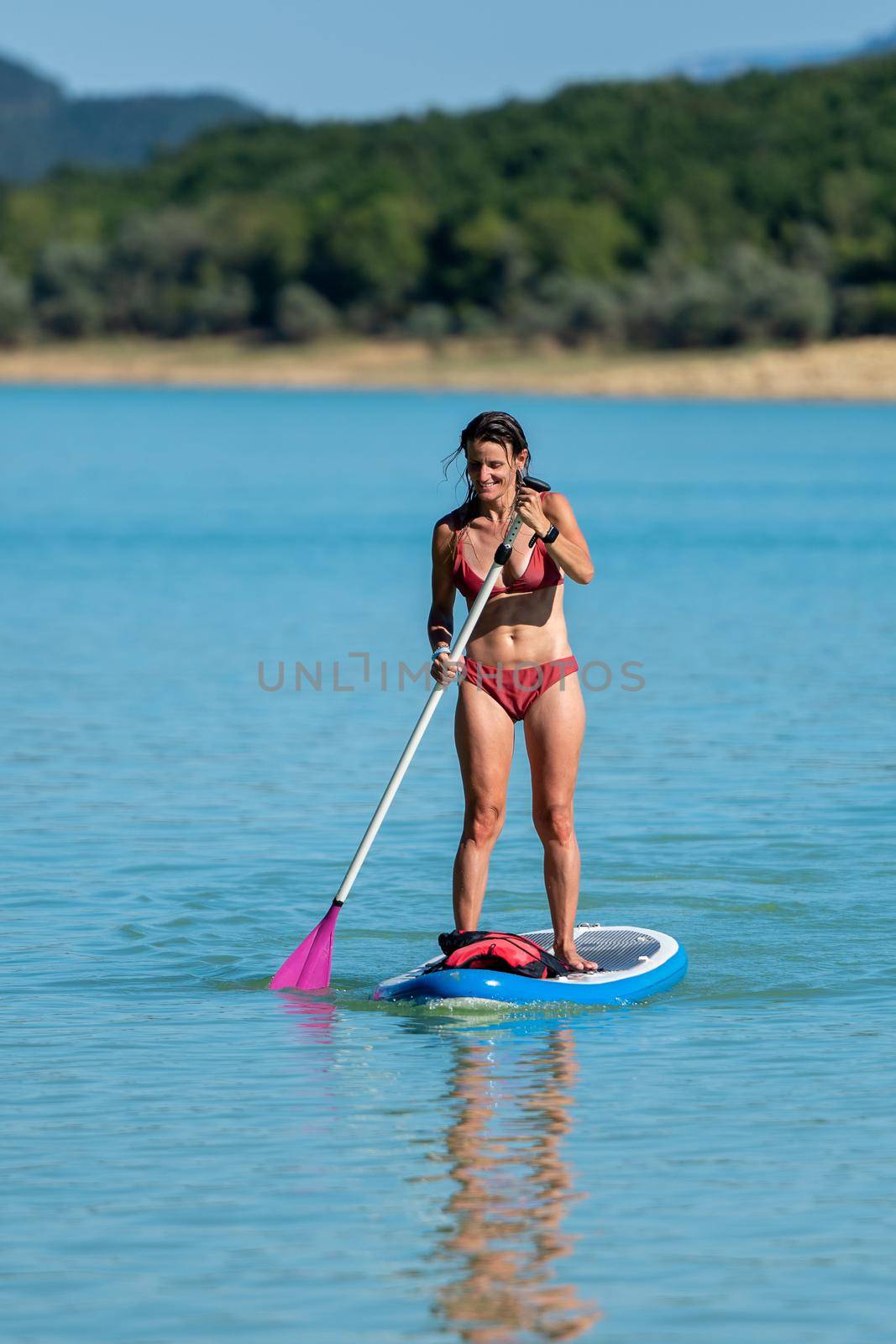 Woman Paddle Surfing on Lake Montbel in Ariege with the boats in the summer of 2022 by martinscphoto