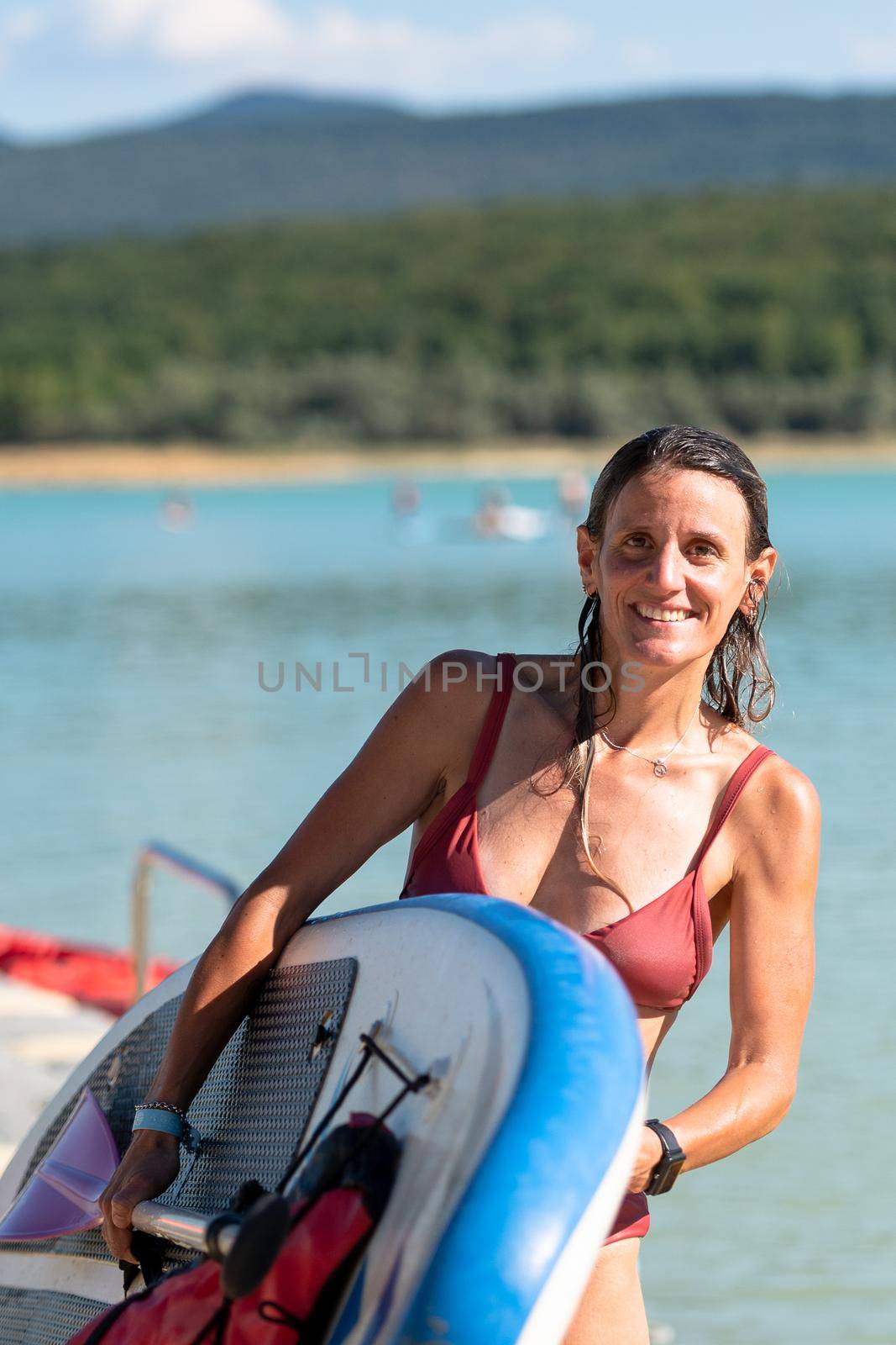 Woman Paddle Surfing on Lake Montbel in Ariege with the boats in the summer of 2022.