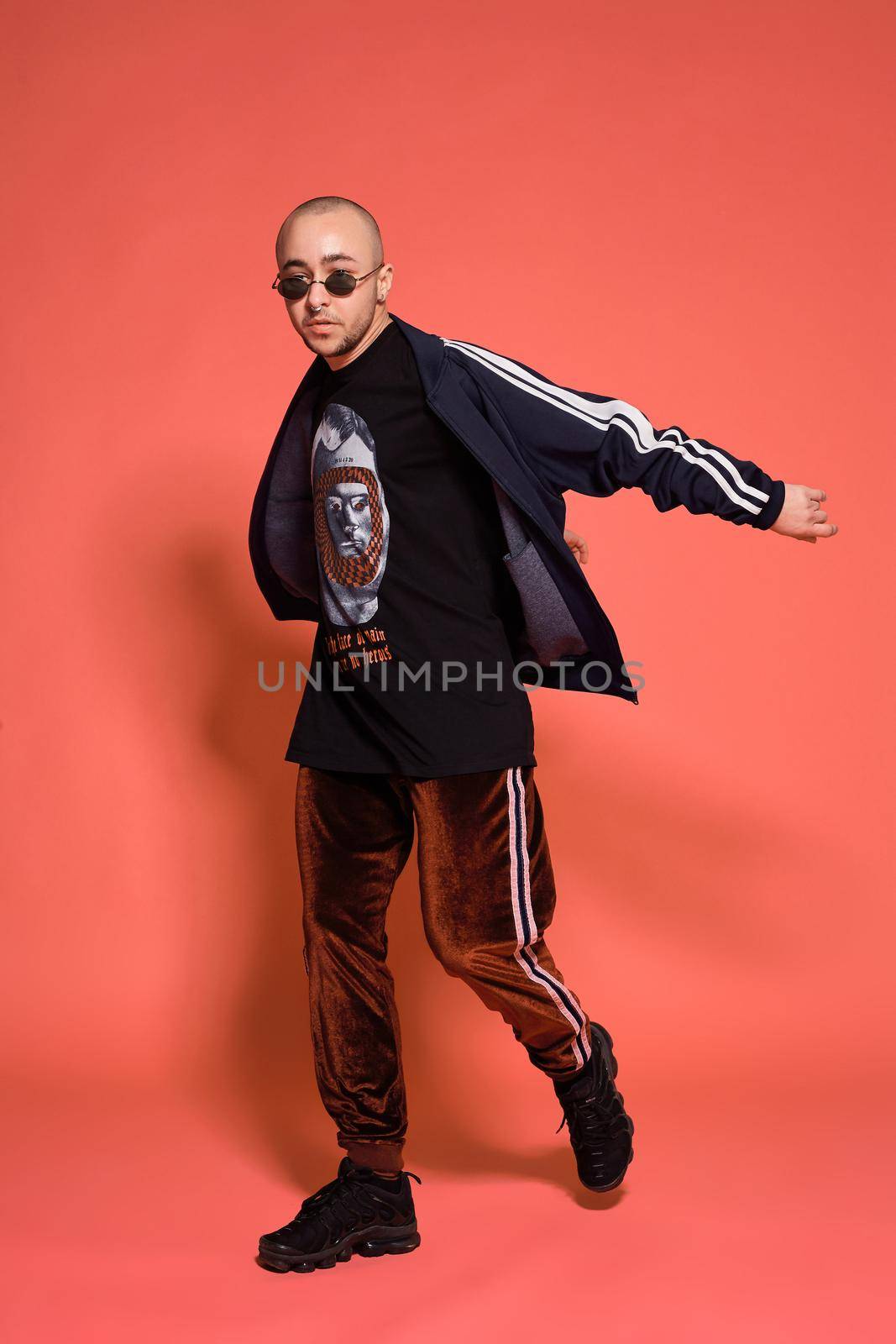 Studio shot of a young tattoed bald man posing against a pink background. 90s style. by nazarovsergey