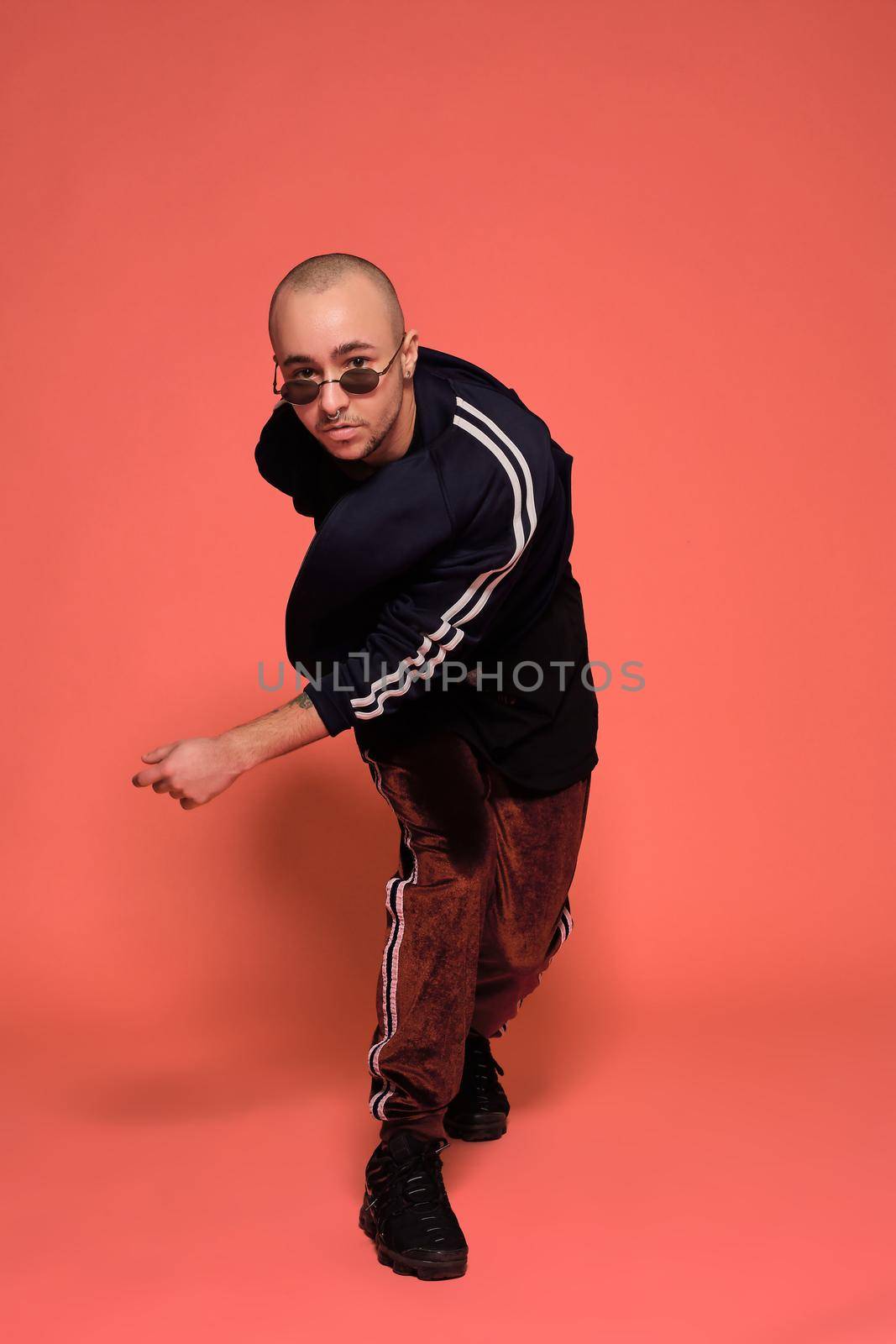 Studio shot of a young tattoed bald man posing against a pink background. 90s style. by nazarovsergey