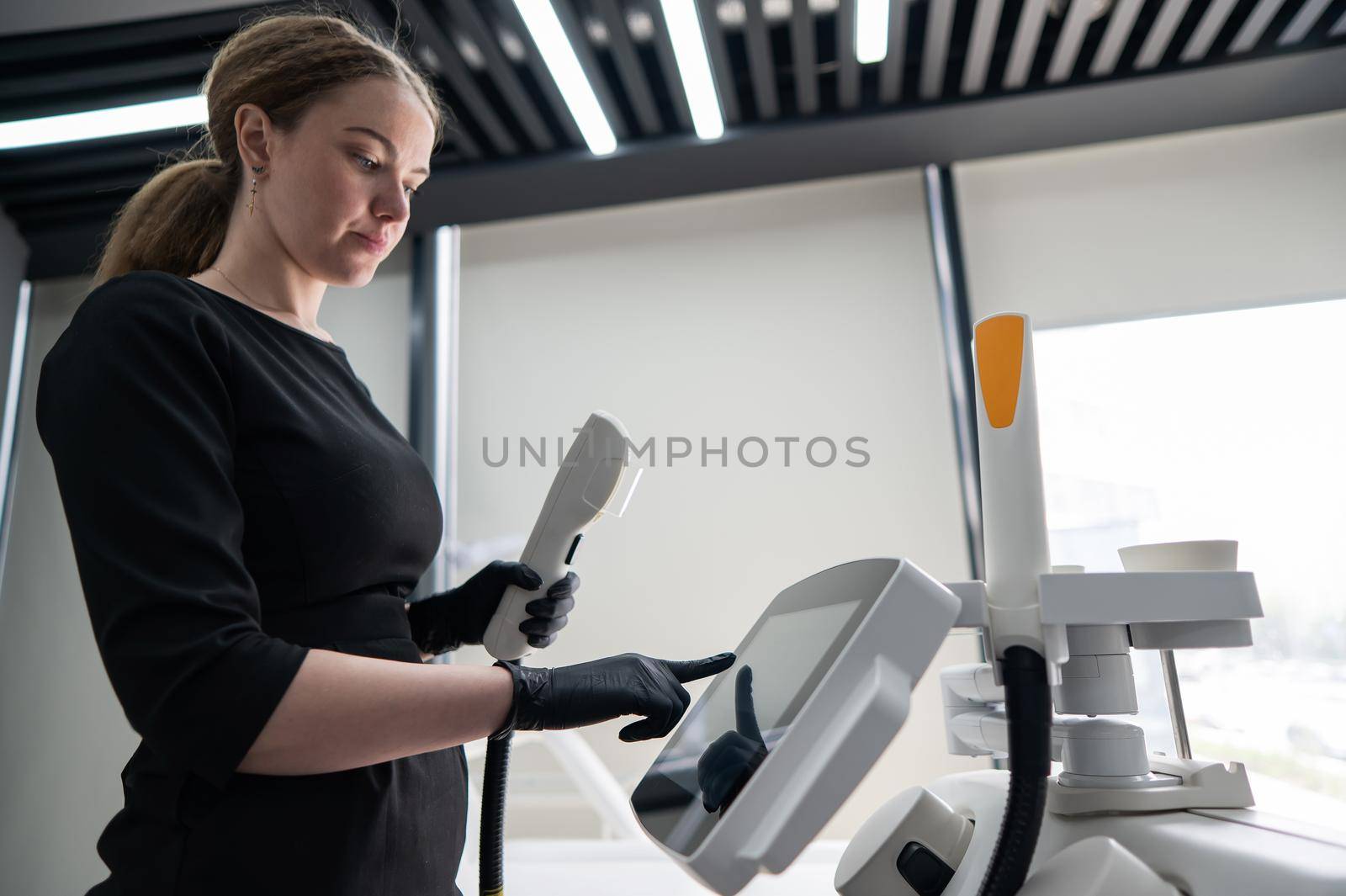 Doctor cosmetologist adjusts the device for photorejuvenation using the touchscreen