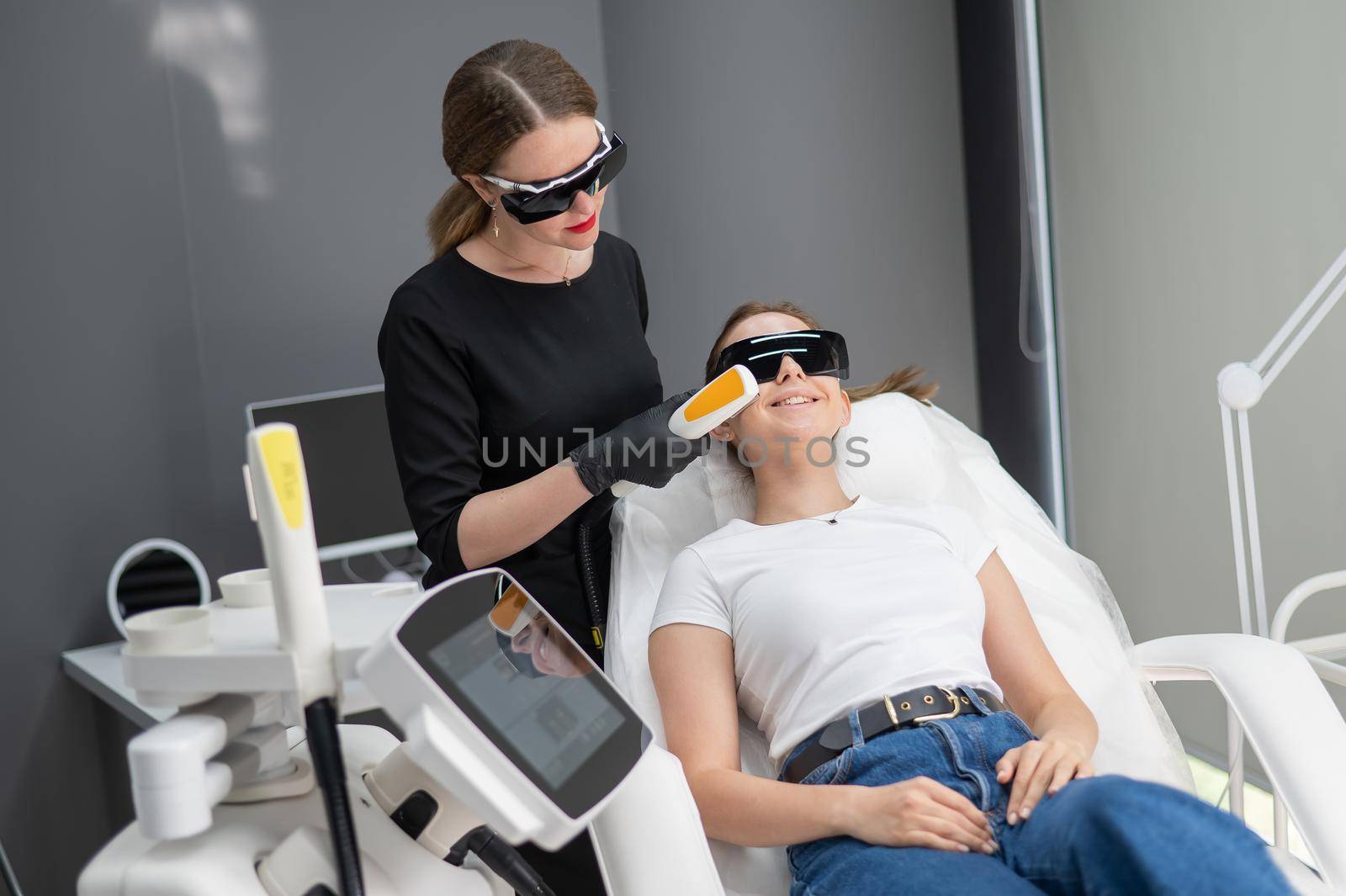 A woman on a couch in goggles undergoing a photorejuvenation procedure. Hardware cosmetology