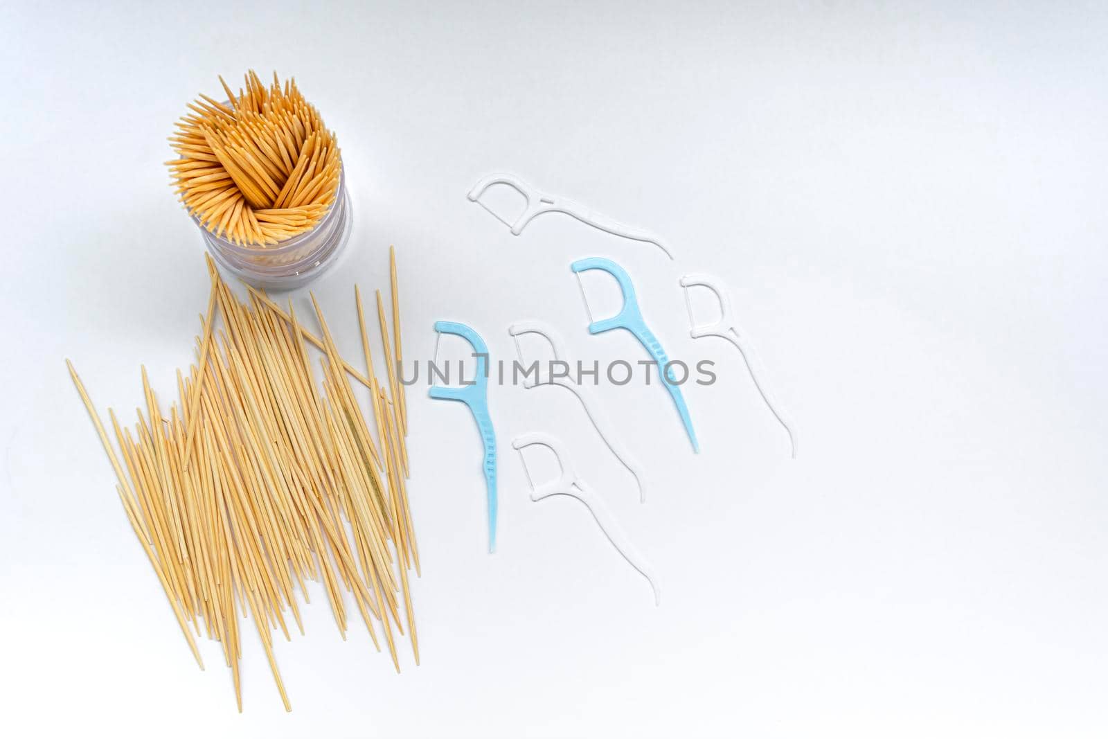 Pile of round wooden toothpicks and toothpick box with a plastic cover on white background. Copy space. Directly above. Flat lay.