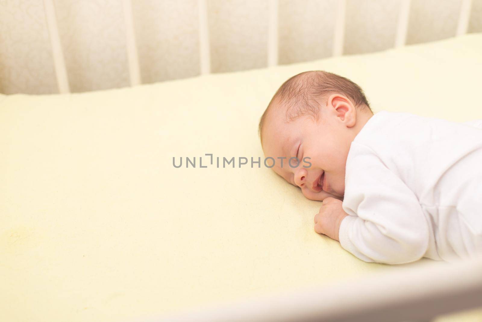 The baby sleeps in the copy space crib . Advertising of children's goods. Illustrating children's articles. A small child. A newborn. A child's dream.