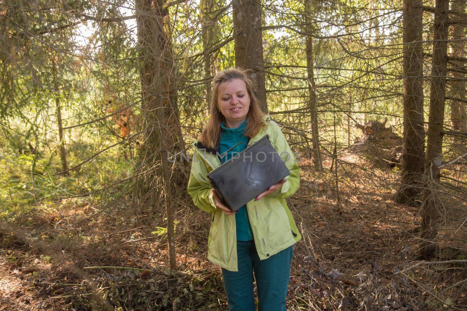 Woman find big metal box. Geocaching in the woods
